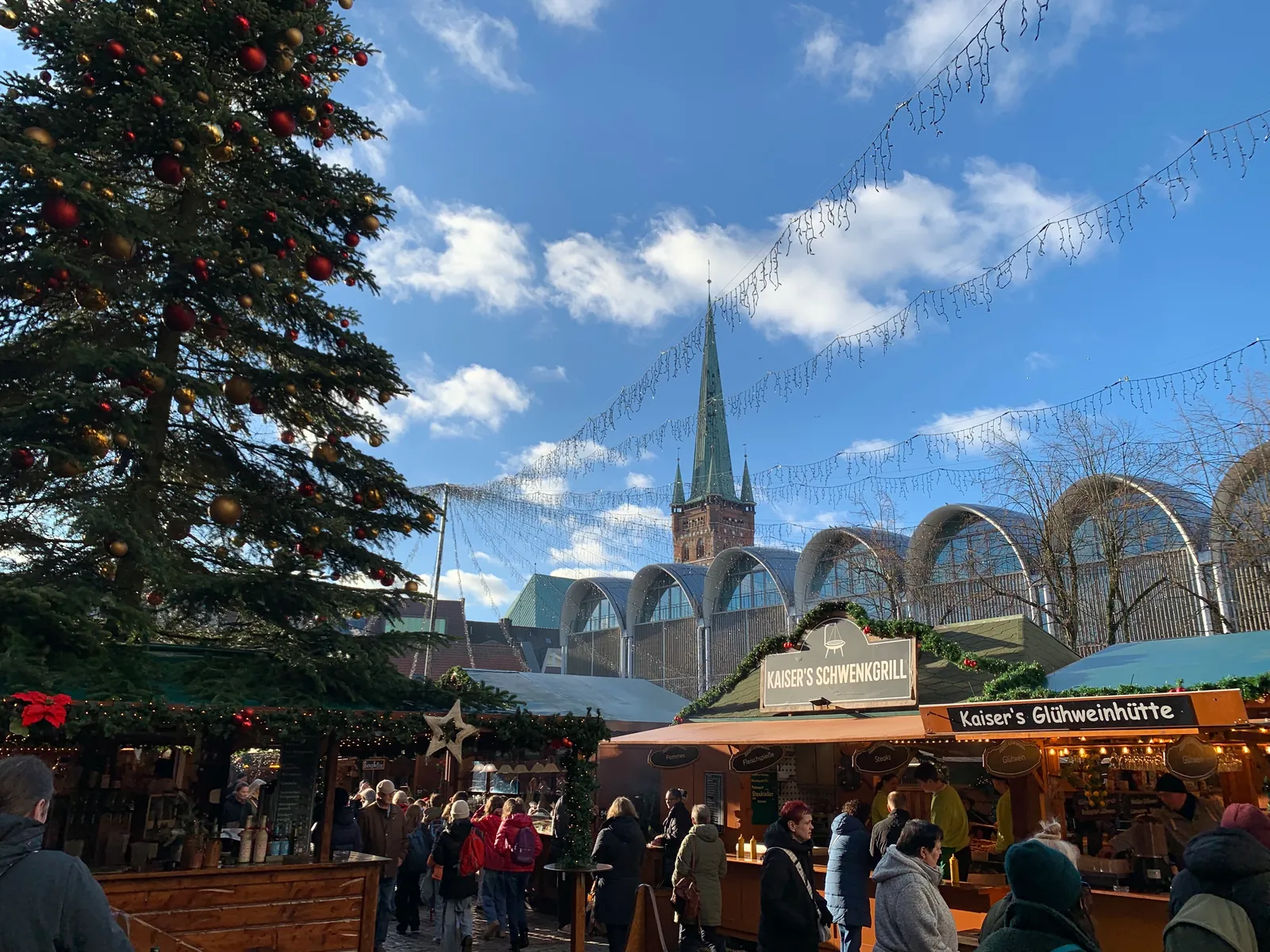 Weihnachtsbaum und Buden auf dem Lübecker Markt, dahinter der Turm von St. Petri
