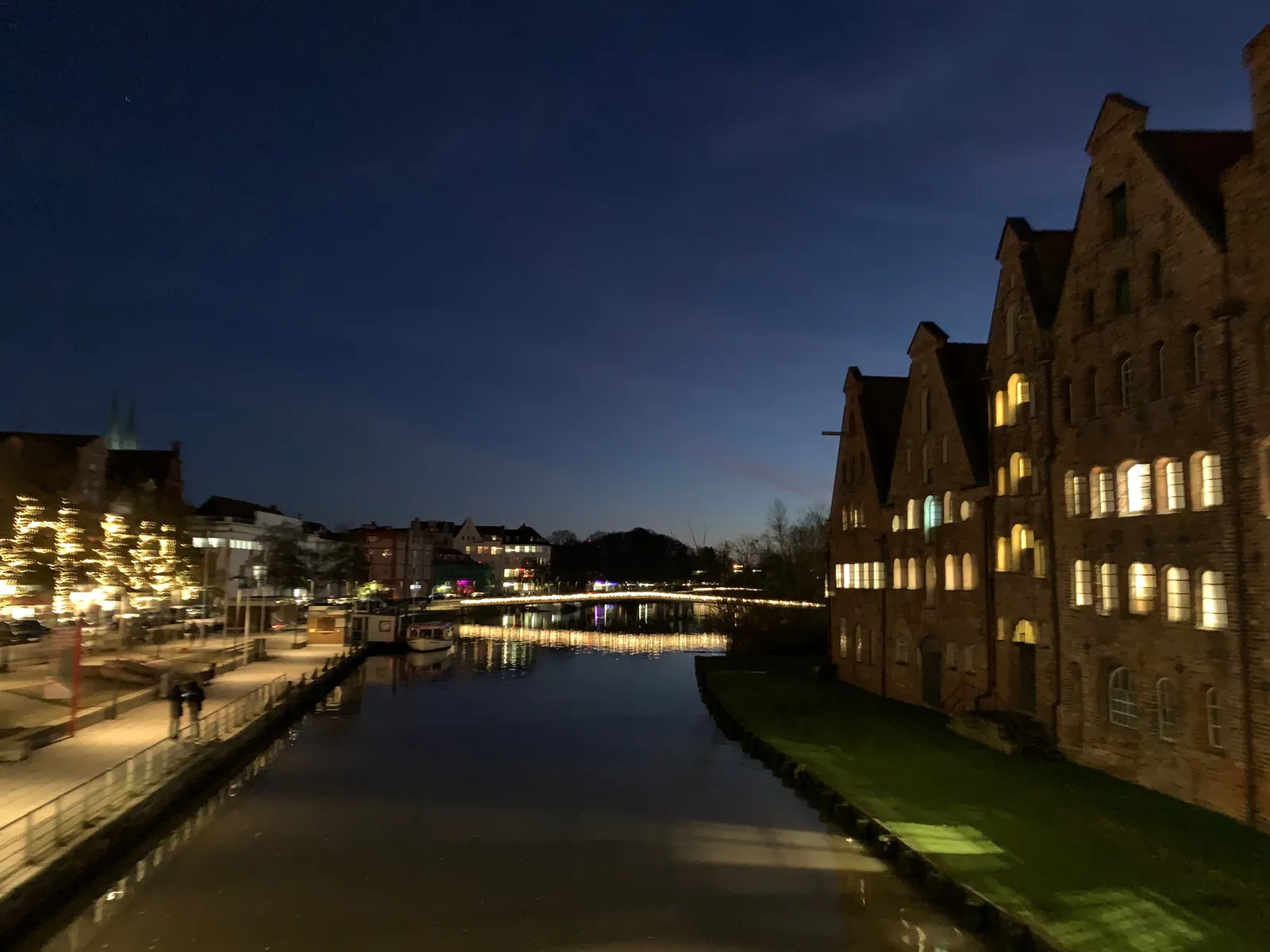 Die Trave in Lübeck am Abend, rechts die beleuchteten Salzspeicher