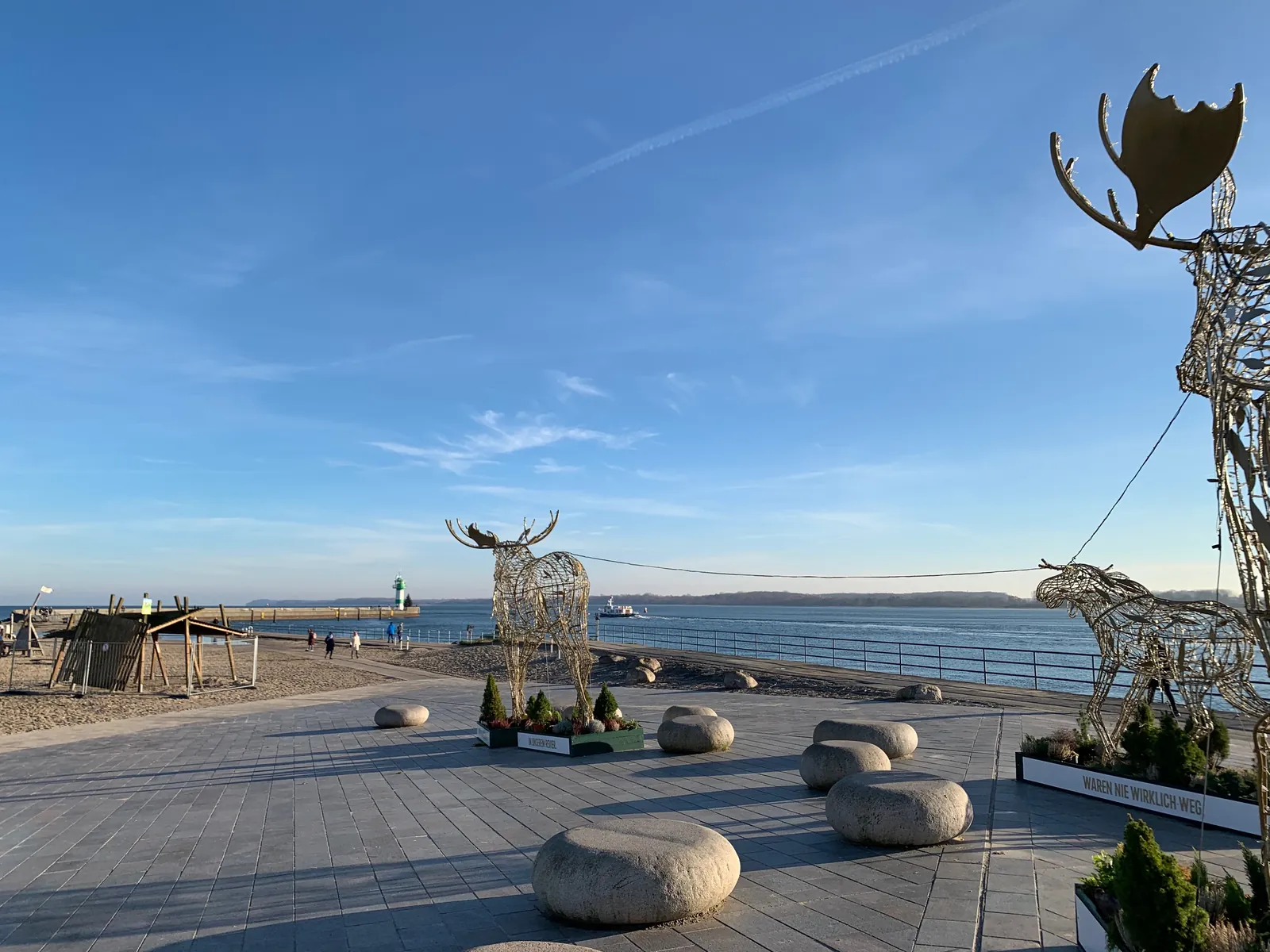 Die Elche aus Draht an den Strandterrassen in Travemünde an einem sonnigen Adventstag, dahinter die Ostsee und die Nordermole